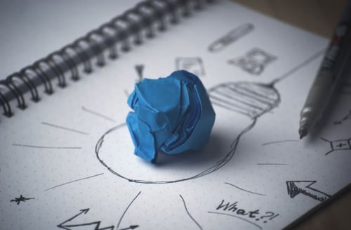 Ball of blue paper on top of a drawing of a lightbulb to represent buyer personas