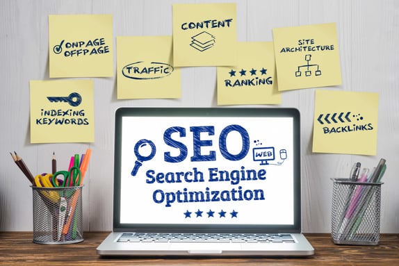 Laptop displaying "SEO" and surrounded by post-it notes