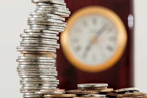 Pile of coins in front of a clock to represent startup marketing costs