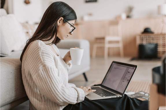 a women drinking a cup of tea whilst using hubspots content assistant