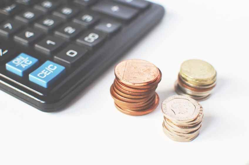 Coins and a calculator on a table representing money & pricing