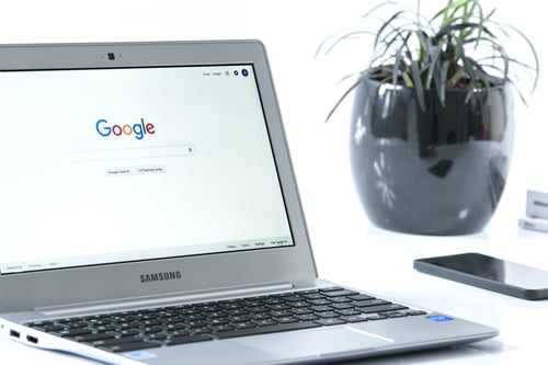 Open laptop displaying Google search page next to a phone and potted plant to represent Google medic update