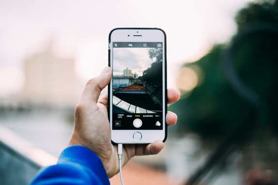Hand holding up phone to take a photo to represent social media lead generation